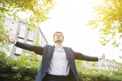 low angle view businessman standing front building outstretching his arms